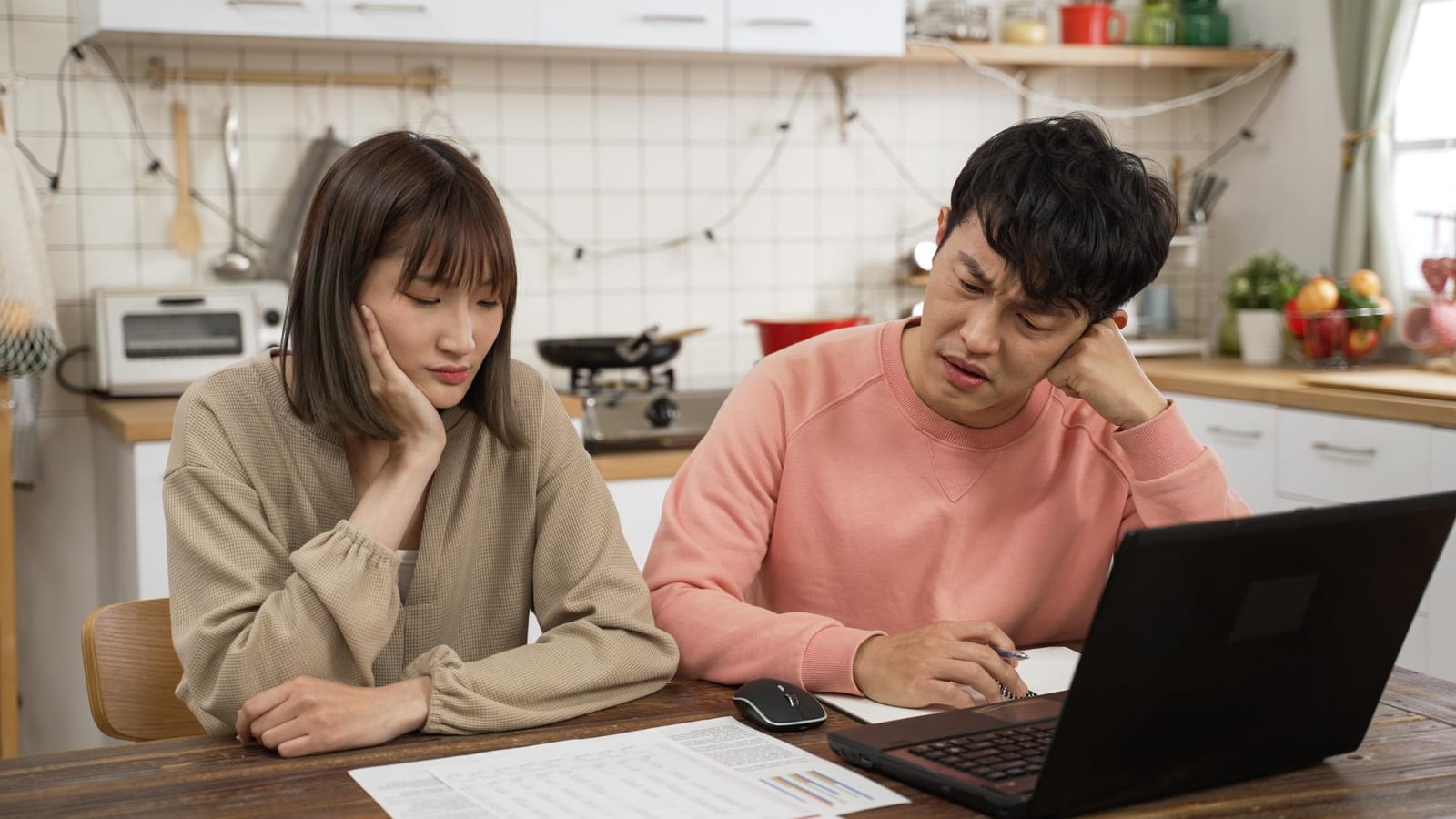 心配そうな表情でノートパソコンと明細書を見つめる夫婦